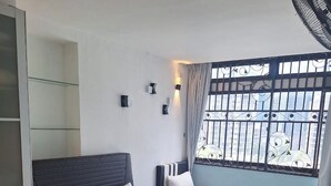 Habitación de hotel con una cama grande, una cama más pequeña, un armario, una ventana con barrotes de metal y un ventilador de techo.