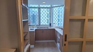 Una cocina compacta con armarios de madera, un lavamanos y un ventanal con un diseño geométrico.