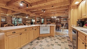 A spacious kitchen with wooden cabinets, a large island, and a checkered floor. - HUGE FAMILY CABIN - 5 bdrm/4.5 bth, Game Room, Hot Tub, Playhouse, Bonfire Pit (Townsend)
