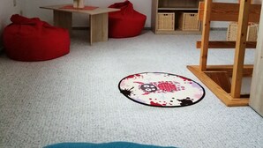A cozy, well-lit attic room with a sloped ceiling, a wooden desk, a red bean bag, a blue cushion, a small round rug, and a wooden bookshelf. - Ferienwohnung "alte Ziegelei 2" Benzingerode ist ein Ortsteil von Wernigerode (Wernigerode)