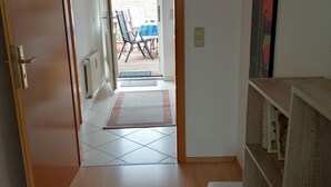 A hallway leading to a balcony with a chair and table, a radiator, and a bookshelf. - Ferienwohnung "alte Ziegelei 2" Benzingerode ist ein Ortsteil von Wernigerode (Wernigerode)
