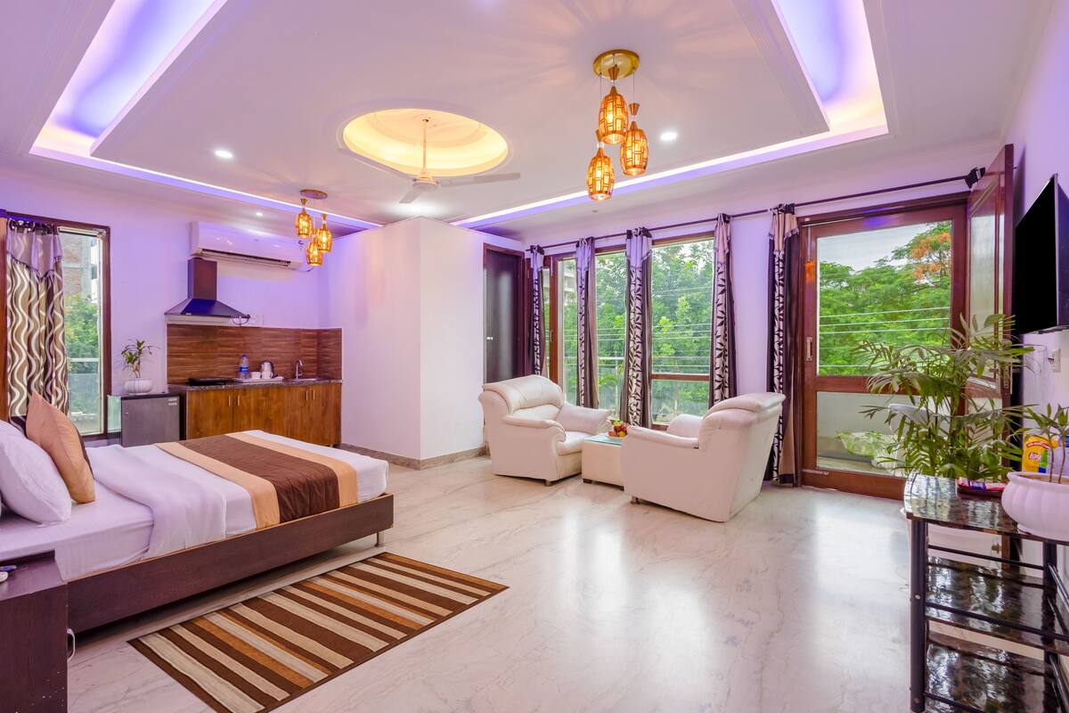 Un dormitorio moderno con cama, zona de estar y vistas a zonas verdes.