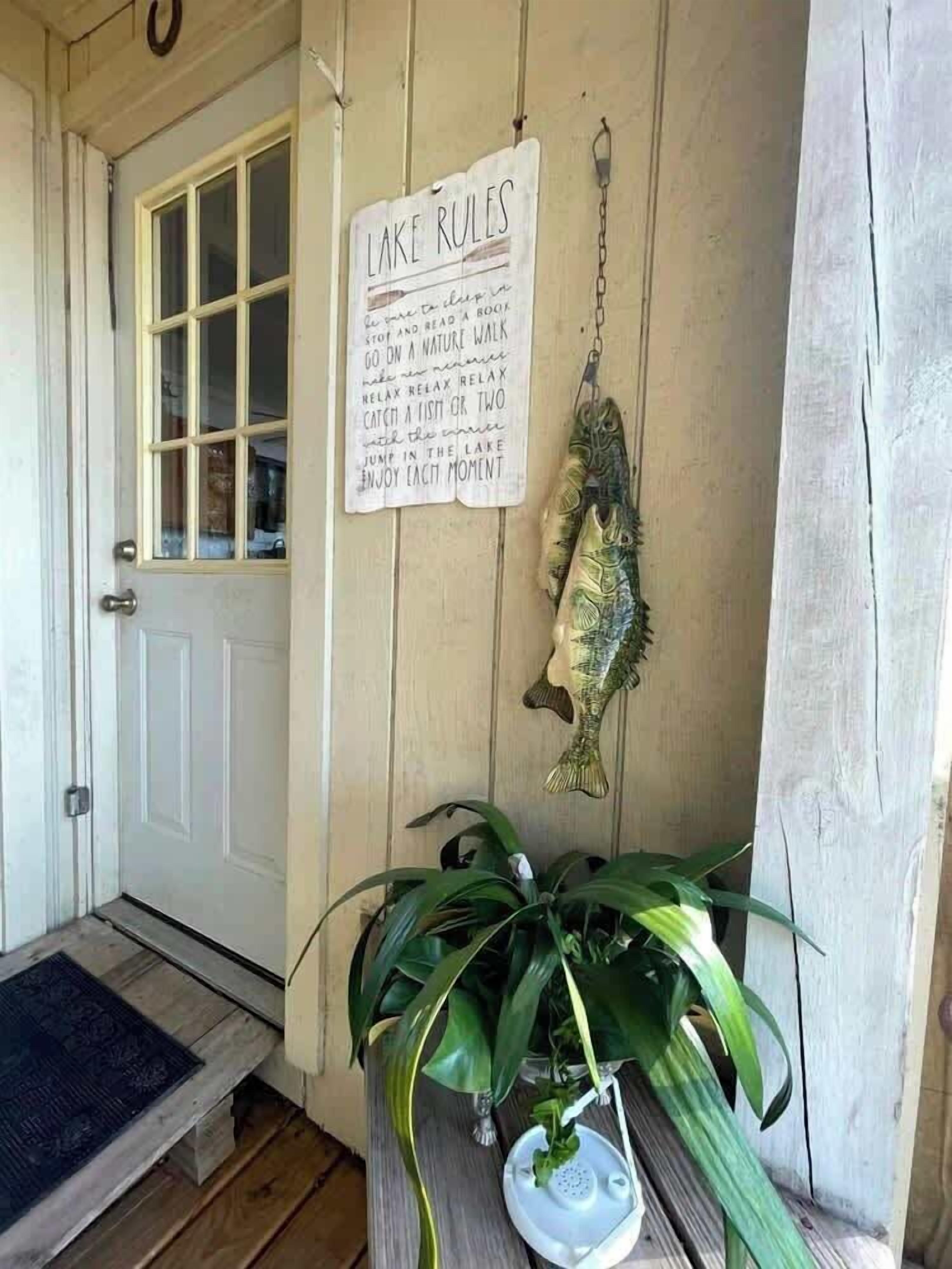 A wooden door with a sign reading "LAKE RULES" and a fish hanging on the wall.