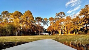 A long, narrow water body with a dock extending into it, surrounded by trees with autumn foliage. - Lakefront Bliss | Kayaks • Paddleboards • Fire Pit • Snowbird Specials (Melrose)