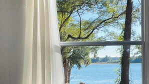 A room with a view of a lake, a towel on the bed, and a sign that says "RELAX". - Lakefront Bliss | Kayaks • Paddleboards • Fire Pit • Snowbird Specials (Melrose)
