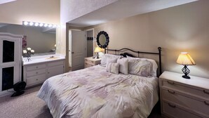 Ein Schlafzimmer mit einem Bett, Nachttischen, einem Schminktisch und einem Deckenleuchter.