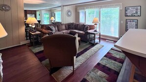Ein Wohnzimmer mit einem braunen Sofa, zwei Lampen, einem Sessel und einem Teppich.
