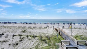 Une plage avec une promenade en bois menant au rivage, des dunes de sable et des parasols de plage.