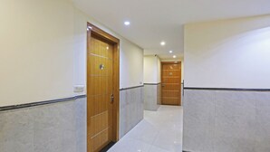 A corridor with marble flooring, wooden doors, and recessed ceiling lighting. - Hotel Smart Lax (New Delhi)