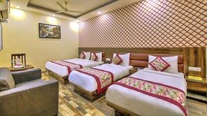 A hotel room with three beds, a sofa, and a ceiling fan. - Hotel Smart Lax (New Delhi)