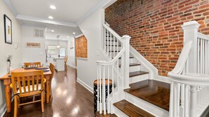 A staircase with white railings and wooden steps leading to a brick wall.