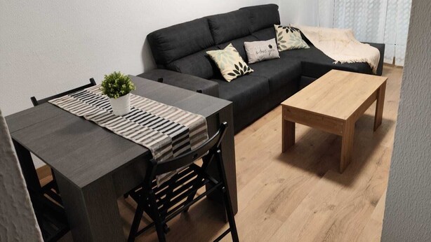 A modern living room with a dark grey sofa, a wooden coffee table, and a striped rug. There are three framed pictures on the wall. - Casa Genoveva . 2ª Linea DE Playa SAN Lorenzo-gijon (Gijón)