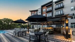 A rooftop pool area with lounge chairs and umbrellas, a bar, and a pool. - Luxurious New Unit|2Bd2Ba|Pool, Golf Sim (Austin)