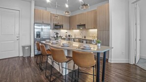 Una cocina moderna con armarios de madera, electrodomésticos de acero inoxidable y una isla central con taburetes de bar.