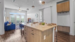 Una cocina moderna con una isla central, armarios de madera e iluminación colgante.