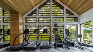 Un gimnasio con cintas de correr, bicicletas estáticas y piso estampado.
