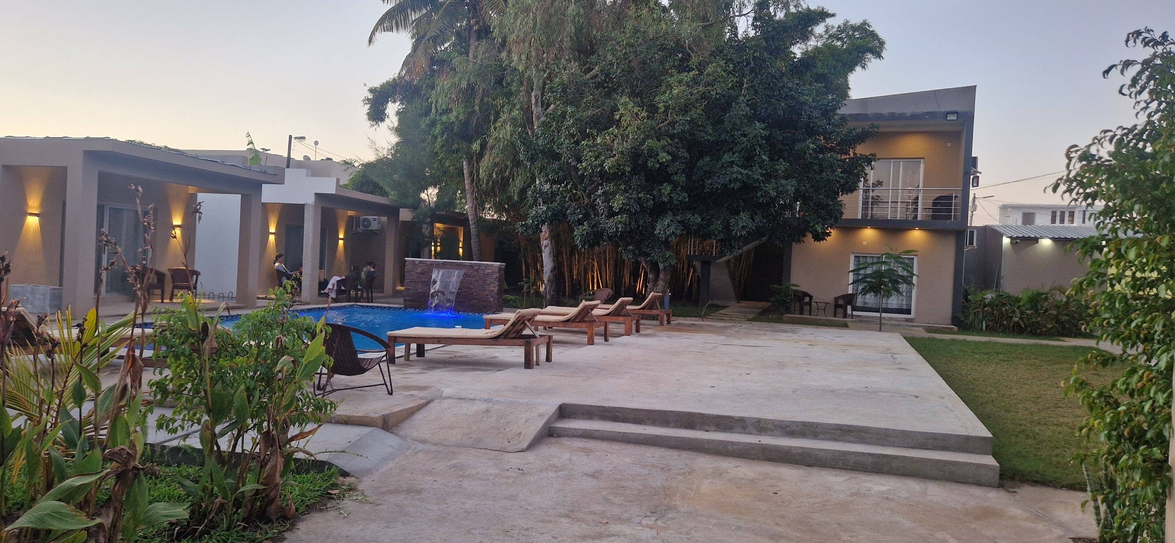 A modern outdoor pool area with lounge chairs and a waterfall feature.