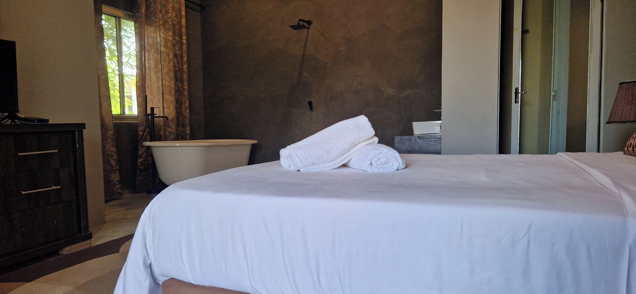 Una habitación de hotel con una cama, una bañera, un armario y una puerta.