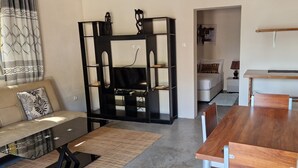 Una sala de estar moderna con un sofá, una mesa de comedor de madera y un mueble de entretenimiento negro.