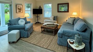 A spacious living room with a high ceiling and skylight, featuring two sofas, a coffee table, and a side table with decorative items.