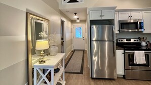 A modern kitchen with stainless steel appliances, a white countertop, and a wooden floor.