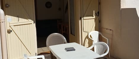 A patio with a table and chairs, a covered area, and a door leading to an interior space.