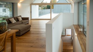Un intérieur moderne avec un plancher en bois, un canapé, une table à manger et un escalier menant à un niveau supérieur.