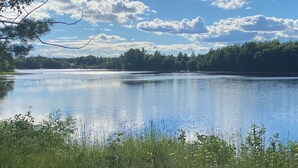 A calm lake with a forested shoreline and a clear sky.