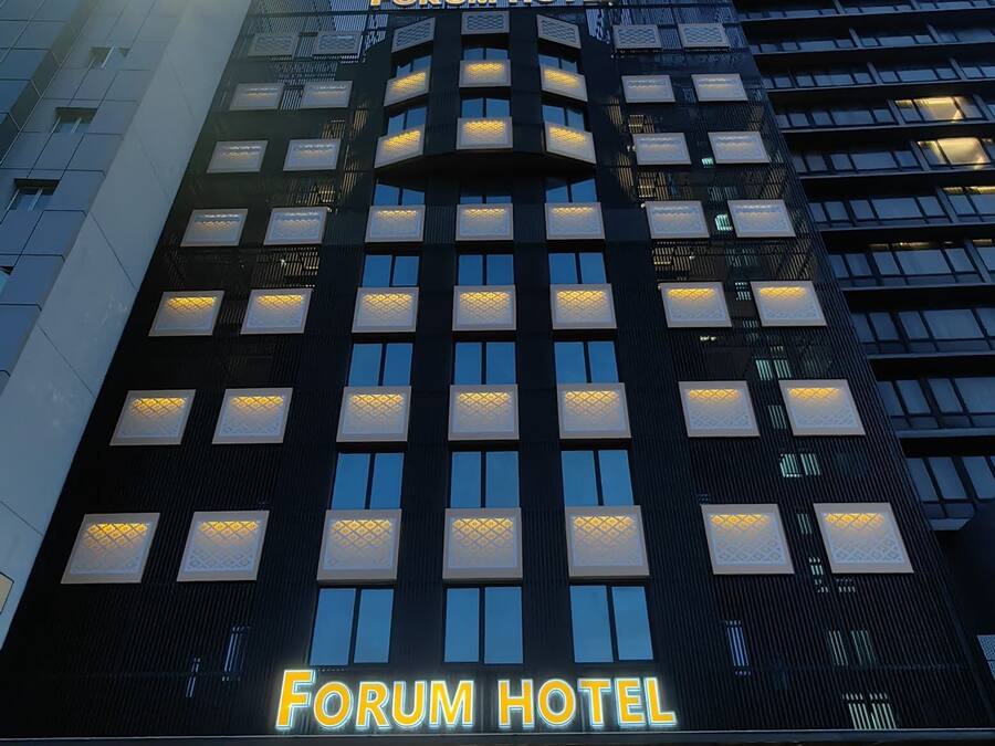 The exterior of the Forum Hotel with a modern design, featuring a prominent entrance and illuminated signage.