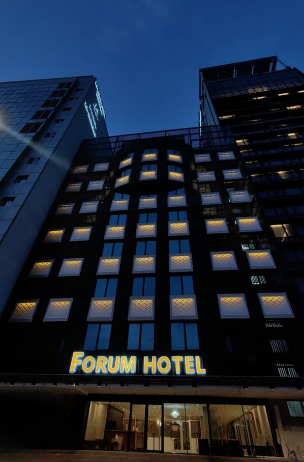 Ein mehrstöckiges Gebäude mit einem gut sichtbaren Schild mit der Aufschrift "Forum Hotel" im Erdgeschoss.
