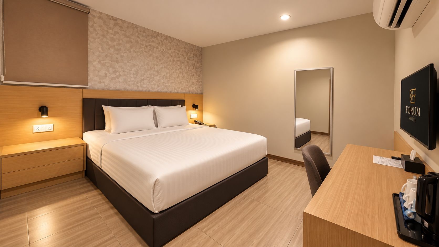 A hotel room with a bed, bedside table, desk, chair, and a television.