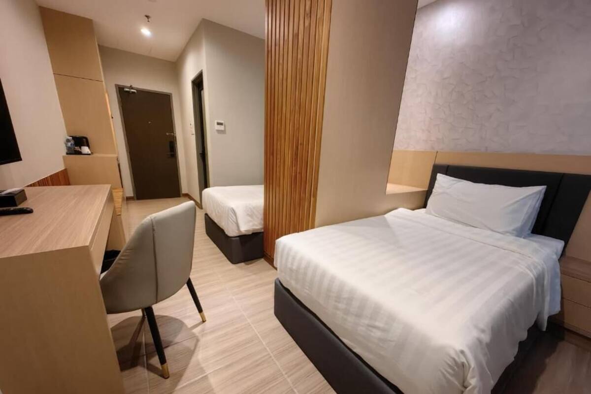 A hotel room with a bed, a desk, and a chair.