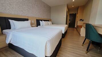 A hotel room with two beds, a desk, and a chair.