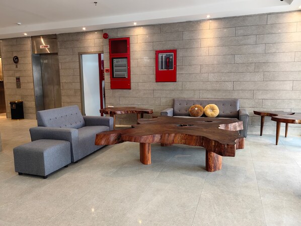 Un vestíbulo moderno con un sofá gris, una mesa de centro de madera y un sofá gris con almohadones decorativos.