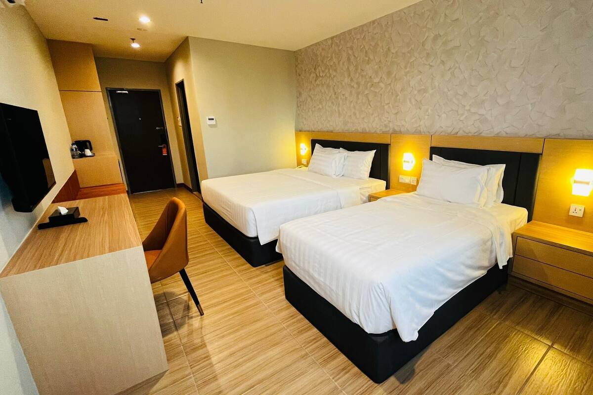 A hotel room with two beds, a desk, and a chair.