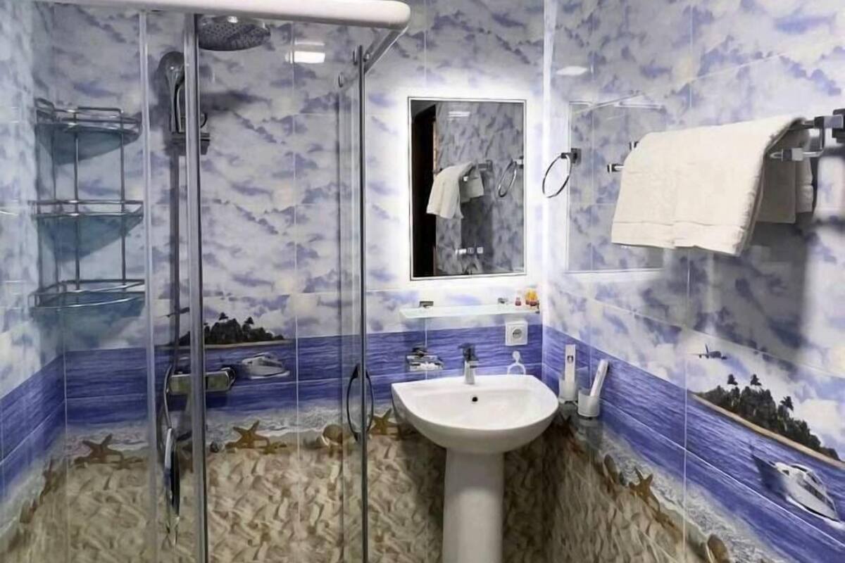 Une salle de bain avec une douche à parois de verre, un lavabo et un miroir.
