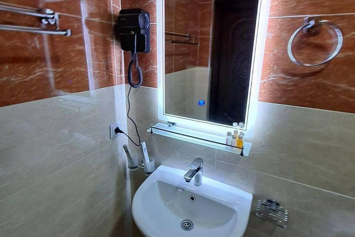 Une salle de bain équipée d’un lavabo sur colonne, d’un sèche-cheveux, d’un miroir avec éclairage et d’un porte-serviettes.