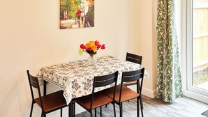 Ein Essbereich mit einem Tisch für vier Personen, einer Blumenvase und einem Bild an der Wand.