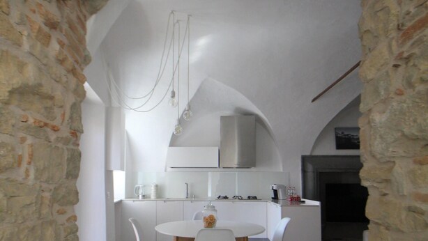 Une cuisine moderne avec des meubles blancs, une table de salle à manger ronde et des chaises en bois.