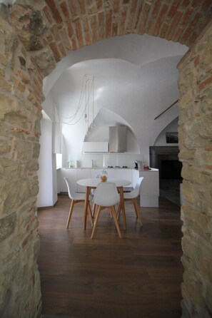 A modern kitchen with white cabinets, a round dining table, and wooden chairs.
