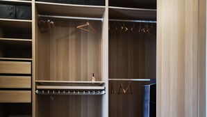Une chambre à coucher comprenant un lit, une armoire avec une tringle pour suspendre les vêtements et une table de chevet avec une lampe.