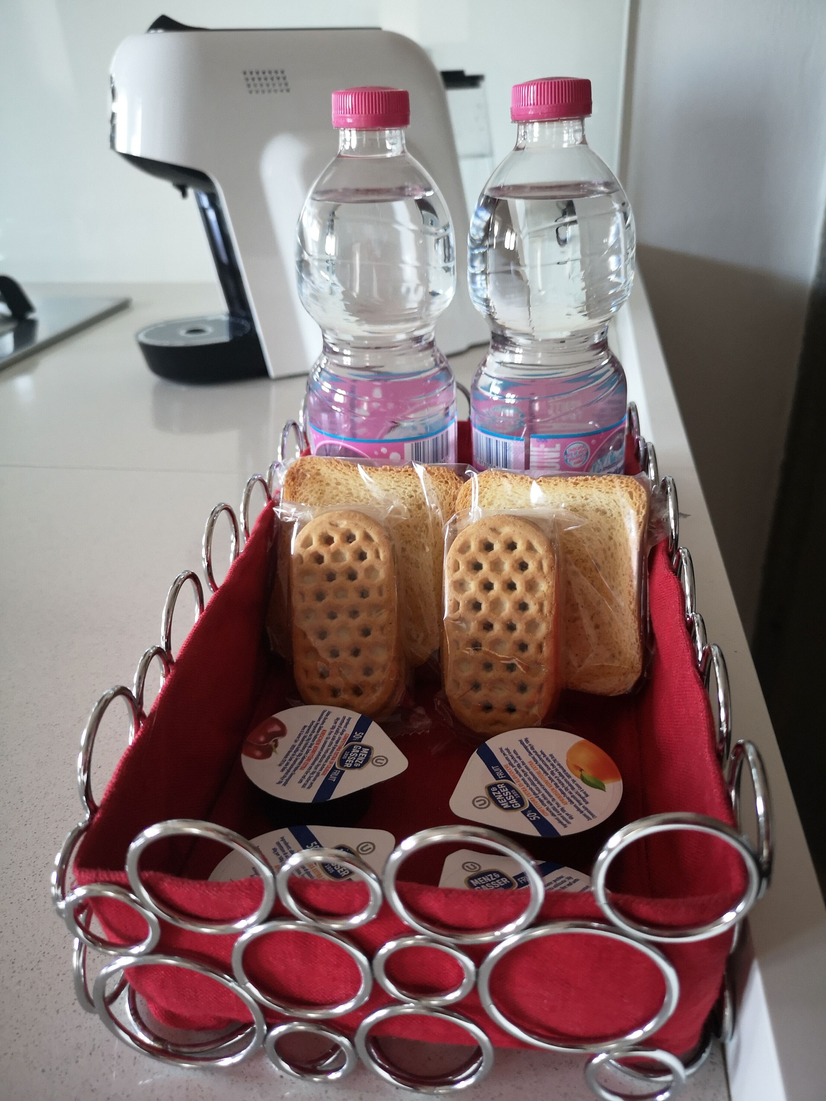 A tray with bottled water, bread, and juice containers on a table.