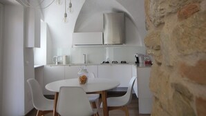Une cuisine moderne avec des meubles blancs, une cuisinière encastrée et un luminaire suspendu.