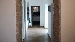 Un couloir avec une arche en pierre menant à une cuisine.