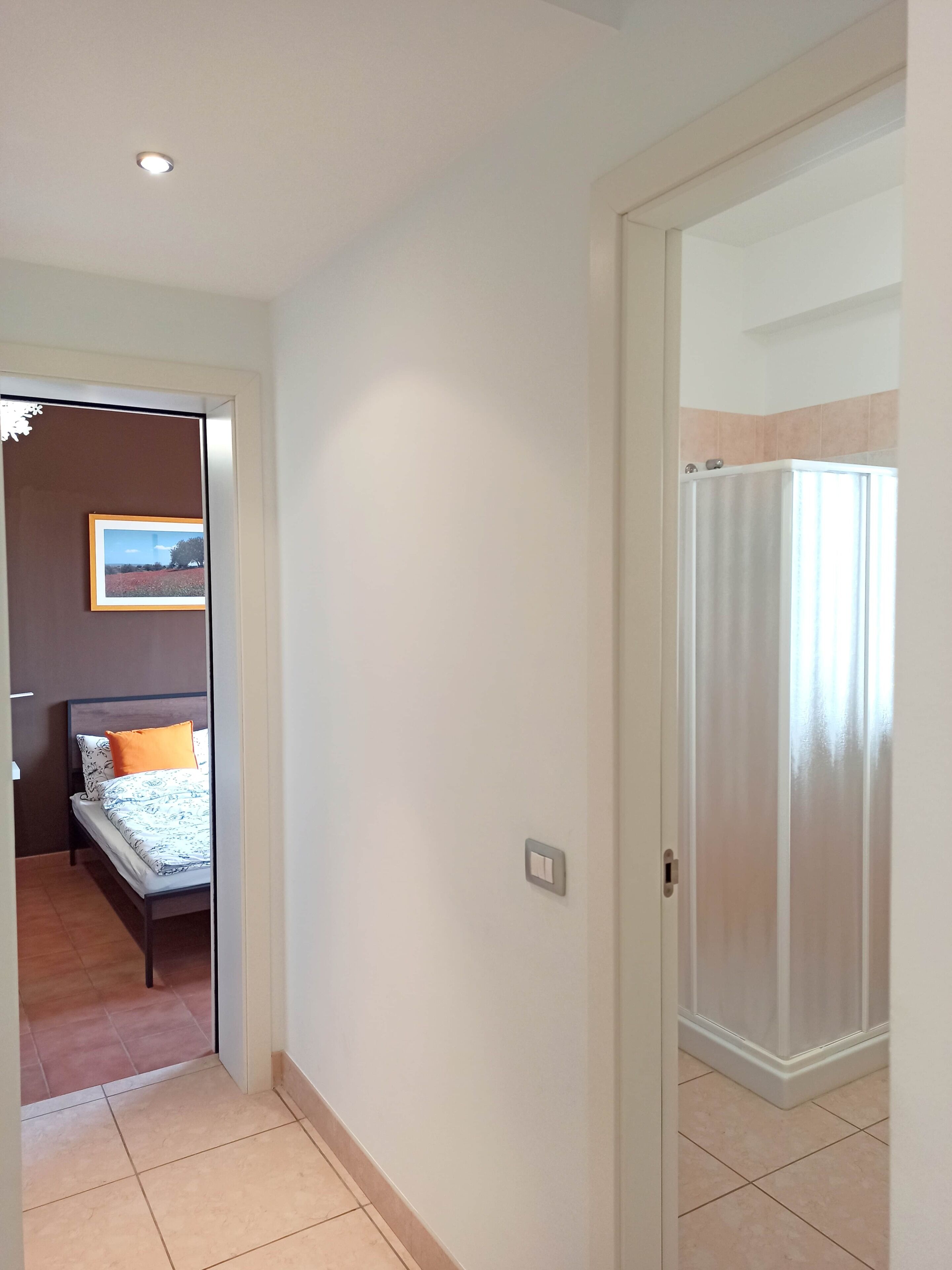 Een hotelkamer met een bed, een foto aan de muur, een douchegordijn en een lichtschakelaar.