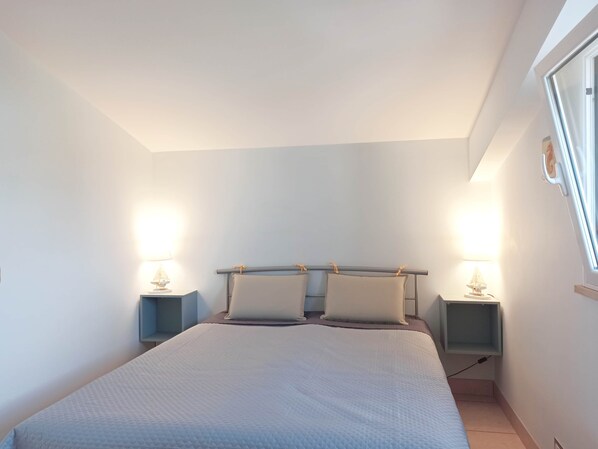 A bedroom with a large bed, two bedside tables with lamps, and a window.