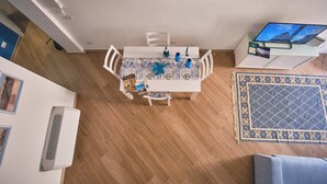 A dining area with a table set for four, a television on a stand, and a patterned rug on the floor. - Magic and Enchantment, comfortable apartment in the heart of Trani's historic center (Trani)