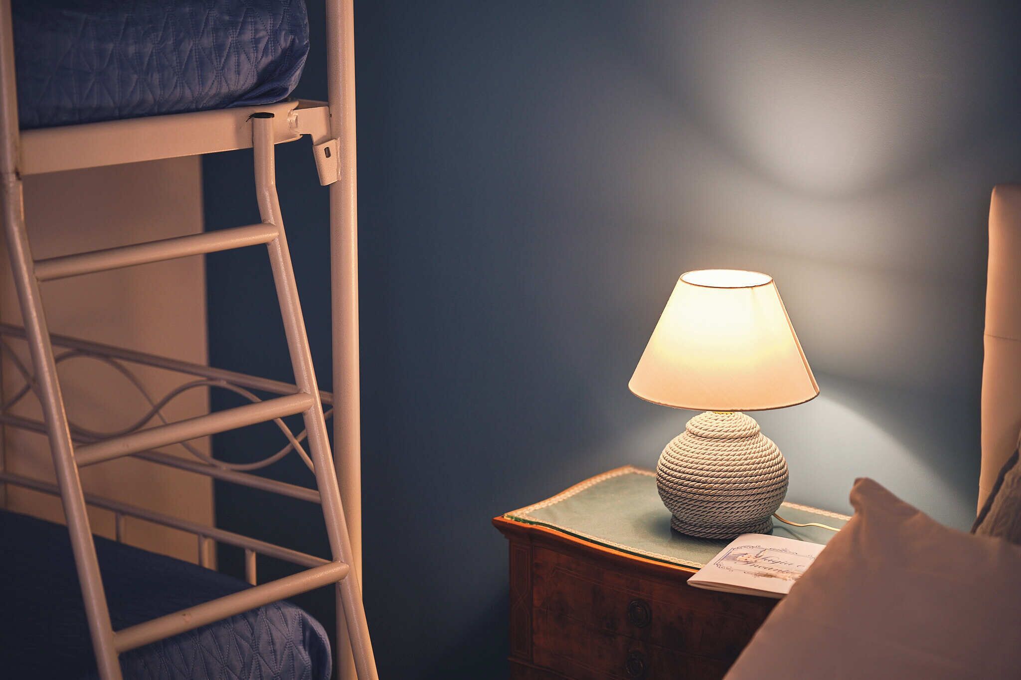 Ein Etagenbett mit einer Leiter, ein Nachttisch mit einer Lampe und ein Buch.