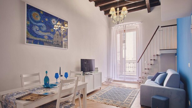 A dining area with a table set for two, a television, and a painting on the wall. - Magic and Enchantment, comfortable apartment in the heart of Trani's historic center (Trani)