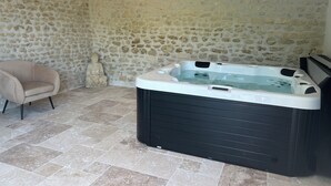 A spa area with a stone wall, a massage chair, and a hot tub.